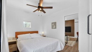 A bedroom with a bed, bedside table, lamp, ceiling fan, window, and a TV in the background. - Modern 1BR Private ADU with Dedicated Parking & Washer Dryer (Citrus Heights)