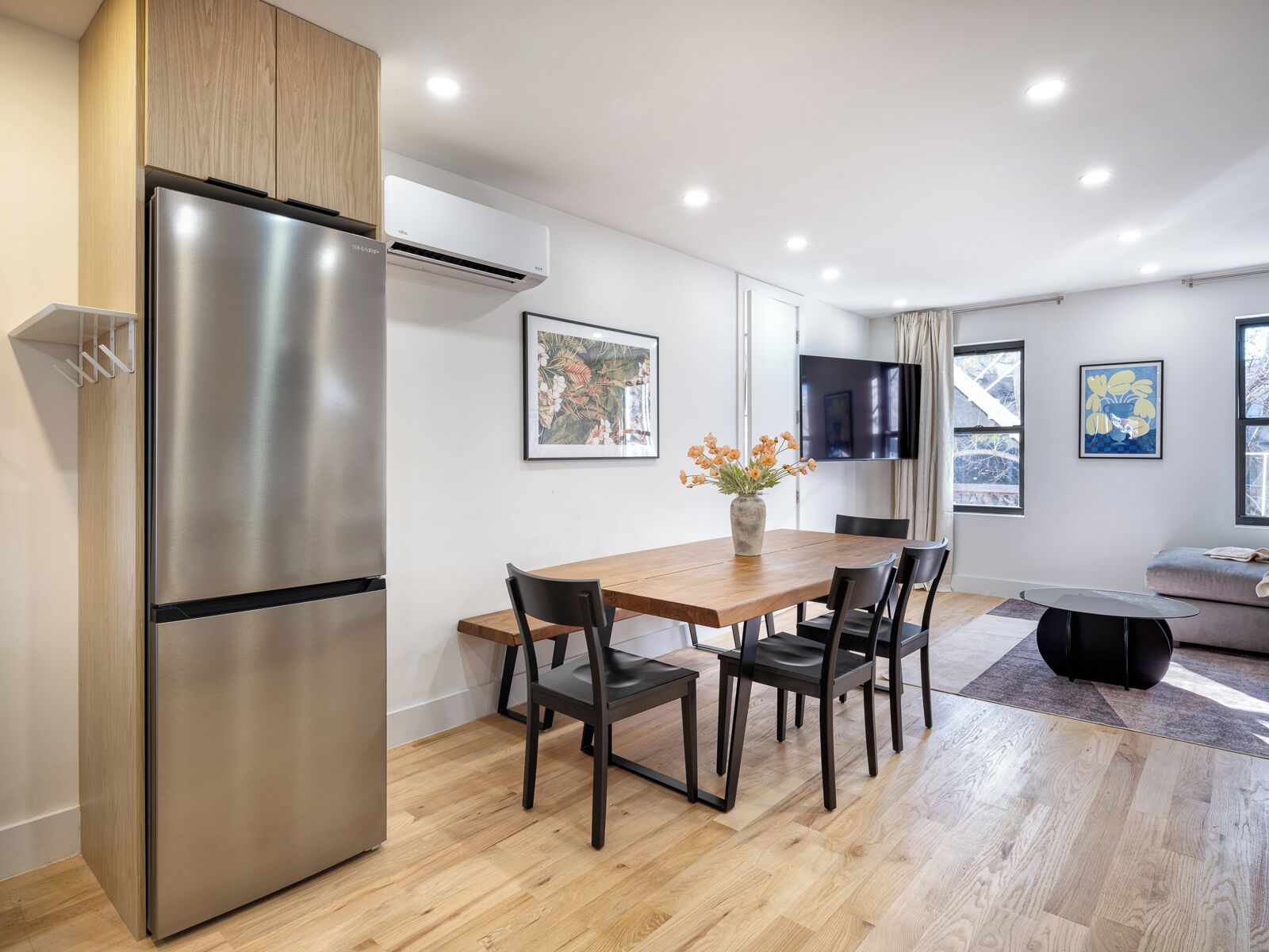 Una cocina moderna con un refrigerador de acero inoxidable, armarios de madera y una mesa de comedor con sillas.
