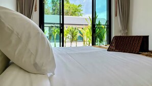 Ein Hotelzimmer mit einem großen Bett und Blick auf Grünflächen sowie ein Gebäude vor dem Fenster.
