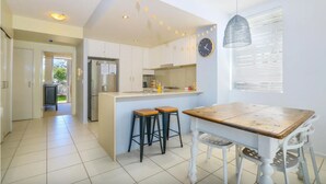 Een moderne keuken met een centraal eiland, barstoelen en een eettafel met stoelen.