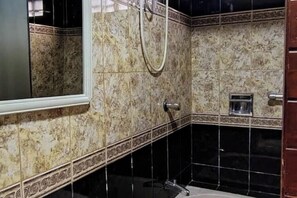 Un baño con ducha, espejo y pared con azulejos.