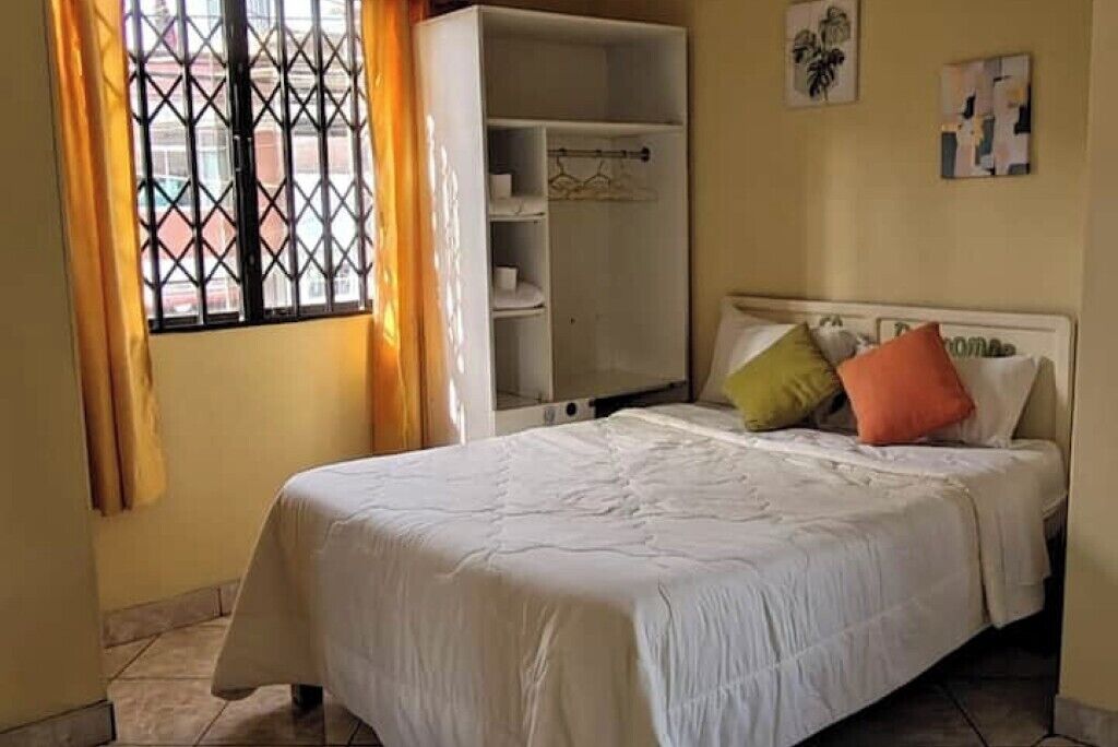 A bedroom with a bed, a wardrobe, and a window with curtains.