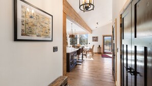 Un corridoio con pavimento in legno, una mappa incorniciata appesa al muro, una zona pranzo con sedie e tavolo, e un'ampia porta con una chiave.