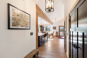 A hallway with wooden flooring, a framed map on the wall, a dining area with chairs and a table, and a large door with a keyhole. - NEW-find serenity at Toca El Cielo Ranch : your peaceful mountain retreat (Lake George)
