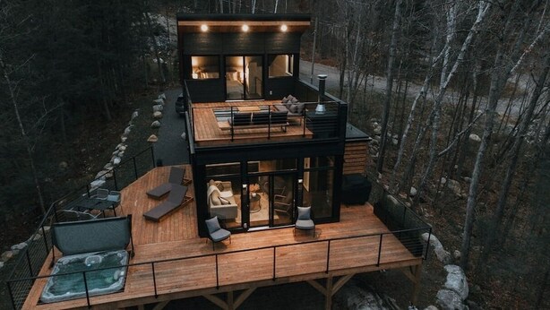 A modern two-story cabin with a deck, outdoor seating, and a fireplace. - Ökohaus Mont-Tremblant: Private Luxury Nordic Eco Cabin with Spa & Sauna (La Conception)