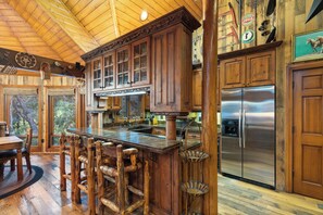 Une cuisine rustique avec des meubles en bois, un réfrigérateur en acier inoxydable et un coin bar avec des tabourets.
