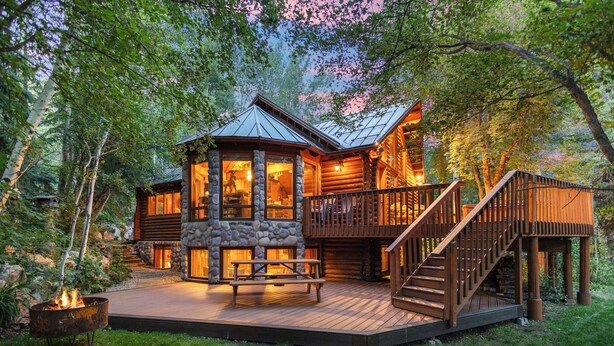 A log cabin with a stone foundation, wooden deck, and a staircase leading to the upper level. - SUNNYSIDE, FLAT YARD, HOT TUB, MOUNTAIN VIEWS, WOOD BURNING FIREPLACE (Sundance)