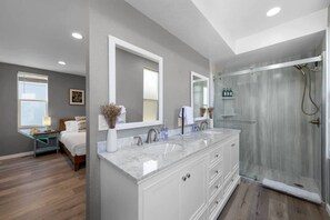 Une salle de bain moderne avec un grand miroir, deux vasques et une douche à l’italienne.