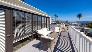 Een balkon met rieten meubels, uitzicht op zee en een heldere lucht.