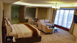 Une chambre d’hôtel avec un grand lit, un canapé, une petite table et un téléviseur.