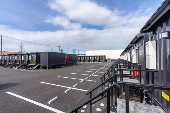 A parking lot with rows of parked containers and a building with a white facade.