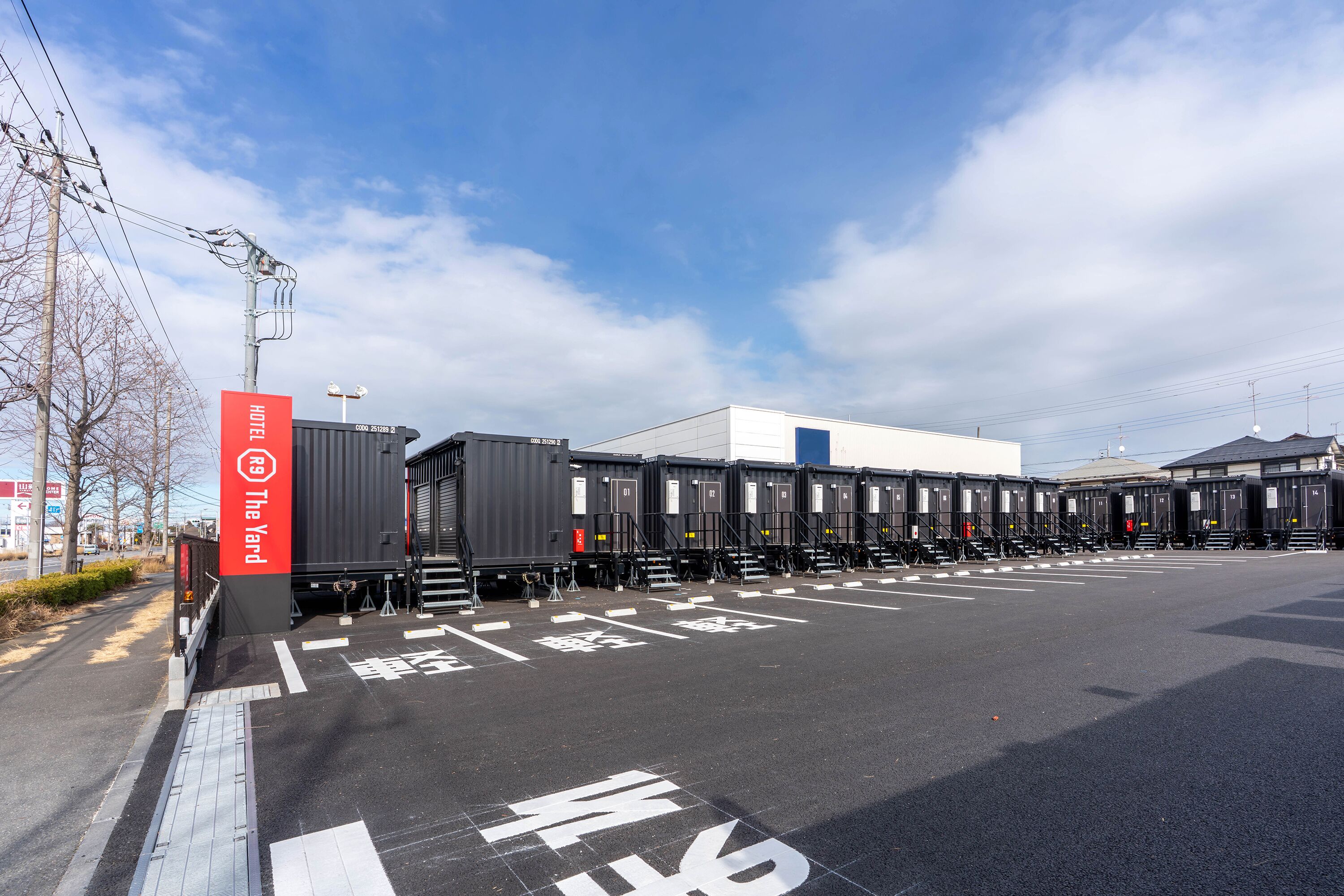 A parking lot with a row of portable toilets and a building in the background.