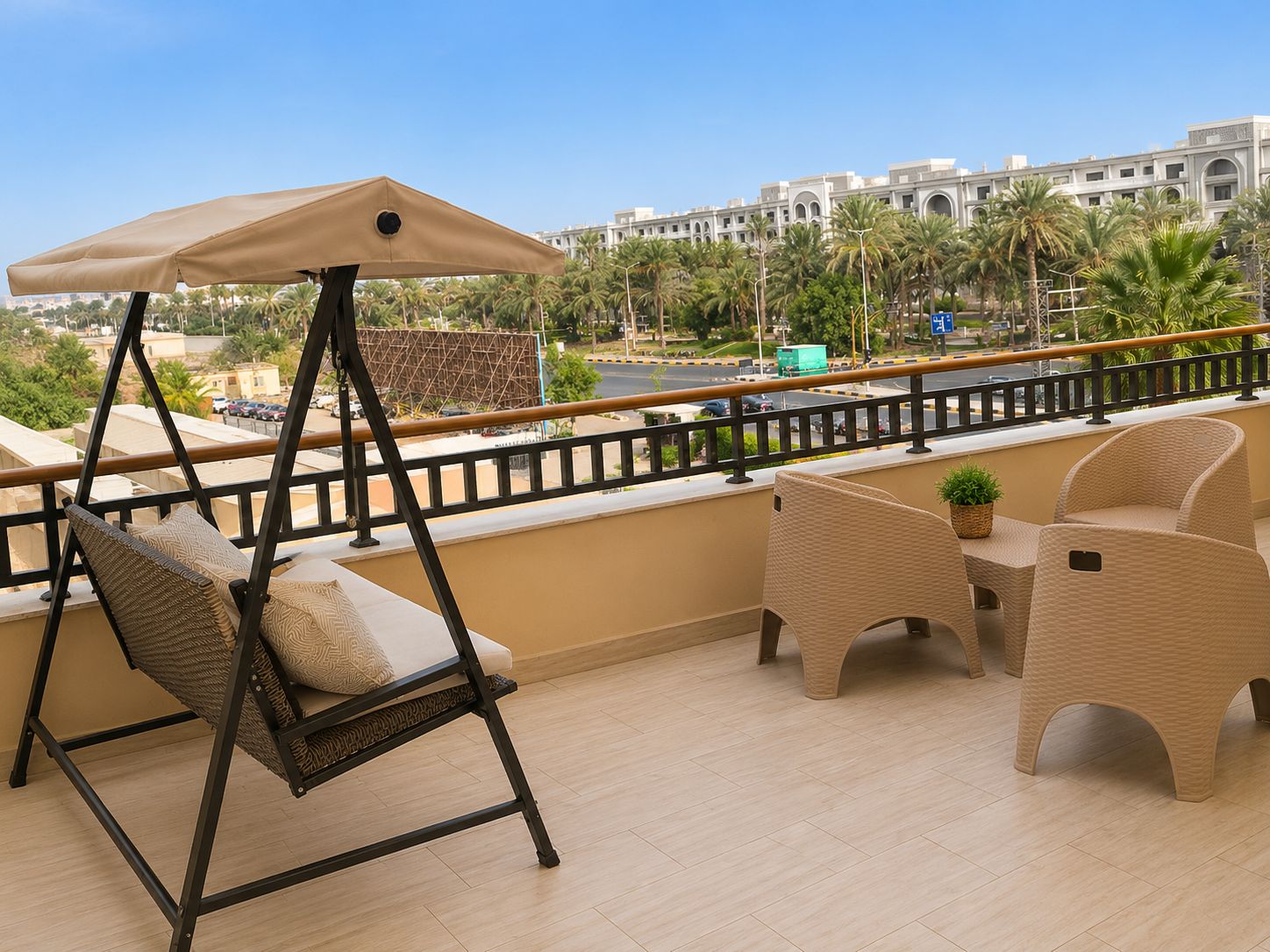 A balcony with a swing chair, a table with chairs, and a view of a cityscape with palm trees.