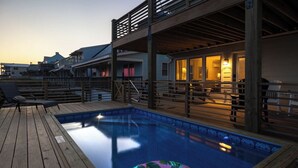 Eine Holzterrasse mit Schwimmbecken, Liegestühlen und einem schwimmenden Ring.