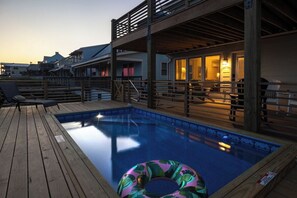 A wooden deck with a swimming pool, lounge chairs, and a floating ring. - Oceanfront Oasis + Guesthouse: 2 Hot Tubs, Pool! (Atlantic Beach)