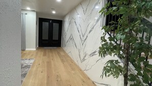A hallway with wooden flooring, a potted plant, a marble wall, and a staircase with a railing. - Enjoyable 4-bedroom house with a beautiful rock water fall slide swimming pool. (Ontario)