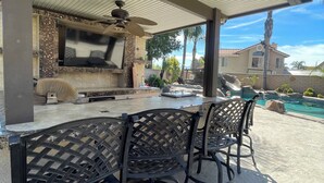 An outdoor patio with a grill, seating, and a pool. - Enjoyable 4-bedroom house with a beautiful rock water fall slide swimming pool. (Ontario)