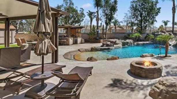 A pool area with lounge chairs, a fire pit, and a covered patio. - Enjoyable 4-bedroom house with a beautiful rock water fall slide swimming pool. (Ontario)