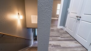 A hallway with a wooden floor, a handrail, and a door with a white frame. - Game Day Getaway • Near Rocky Top Sports World • Sleeps 6 • Quiet Neighborhood (Gatlinburg)