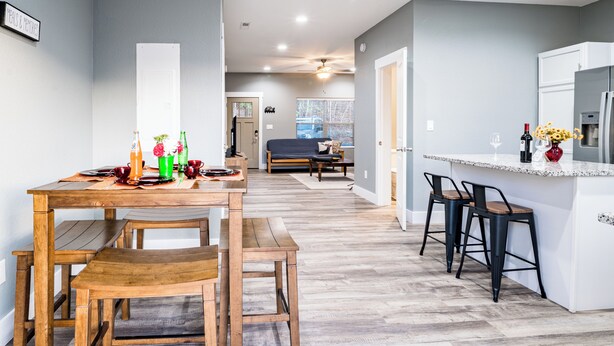 A modern kitchen with a wooden dining table, bar stools, and a built-in island. - Game Day Getaway • Near Rocky Top Sports World • Sleeps 6 • Quiet Neighborhood (Gatlinburg)