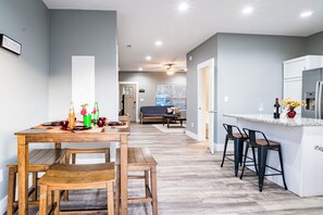 Une cuisine moderne avec une table à manger en bois, des tabourets de bar et un îlot central intégré.