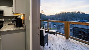 A kitchen with a view of a deck and forest. - Game Day Getaway • Near Rocky Top Sports World • Sleeps 6 • Quiet Neighborhood (Gatlinburg)