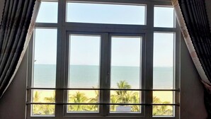 Ein Zimmer mit großem Fenster mit Blick auf Strand und Meer.