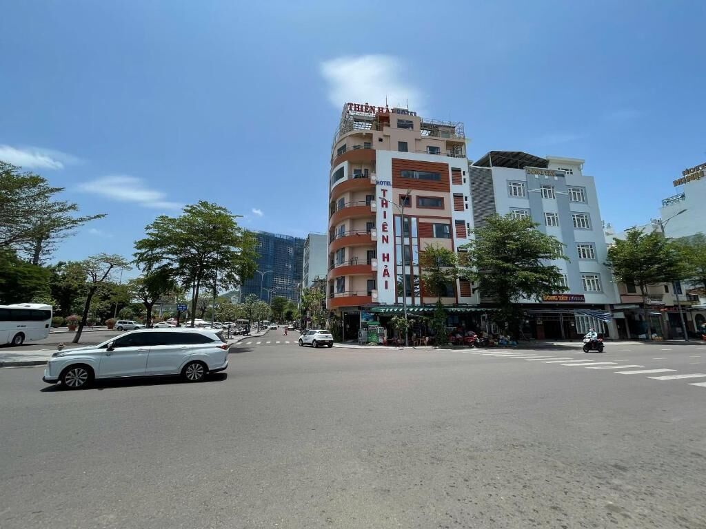 A multi-story hotel with a prominent sign, a street view with vehicles, and surrounding buildings.