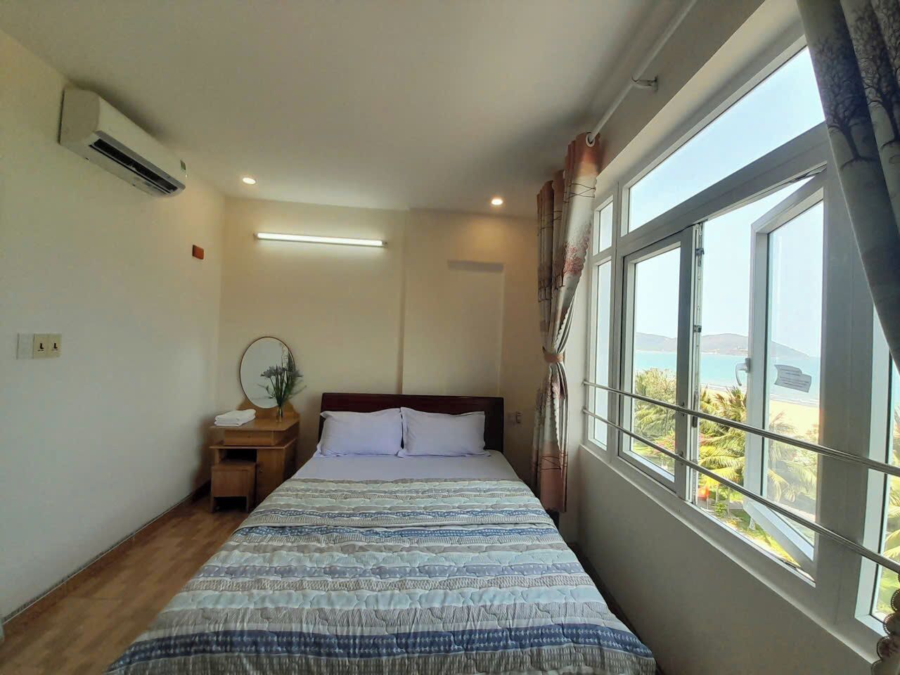 A bedroom with a bed, bedside table, and a window with a view.