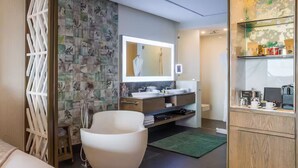 Ein modernes Badezimmer mit einer freistehenden Badewanne, einem großen Spiegel und einem Waschtisch mit Spüle und Ablagefläche.