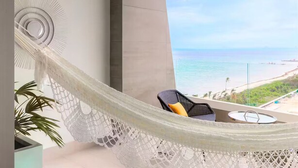 Eine Hängematte auf einem Balkon mit Blick auf Strand und Meer.