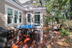 A wooden deck with a ping pong table, outdoor seating, and a pergola. - Enjoy sun-kissed Island days at this recently-built four-bedroom/ 3.5-bath (Bald Head Island)