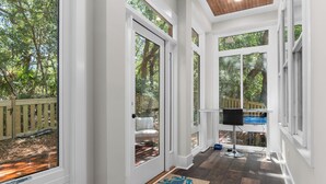 A covered porch with a wooden deck, a chair, and a television. - Enjoy sun-kissed Island days at this recently-built four-bedroom/ 3.5-bath (Bald Head Island)
