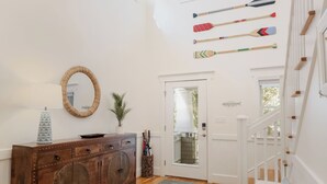 Ein geräumiges Zimmer mit Holzboden, einer weißen Treppe und einer Sammlung von Schlägern an der Wand.