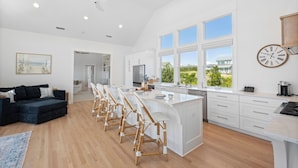 A spacious kitchen with a central island, large windows, and a view of the outdoors. - VIEWS of the Atlantic will mesmerize you from The Glass Slipper (Bald Head Island)