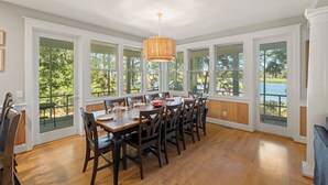 Un comedor con una gran mesa de madera, seis sillas y una lámpara colgante.
