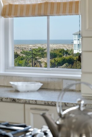 A kitchen with a view of the beach and a building across the water. - Chippin' & Sippin' gives you the best of the beach AND the golf course (Bald Head Island)