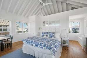 A bedroom with a large bed, a desk, and a chair. There are windows on two sides of the room. - Welcome to one of the Island (Bald Head Island)