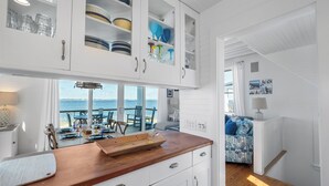 A kitchen with white cabinets, a wooden countertop, and a view of the sea. - Welcome to one of the Island (Bald Head Island)