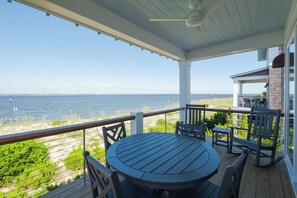 A covered outdoor deck with a table and chairs, overlooking a body of water. - Welcome to one of the Island (Bald Head Island)