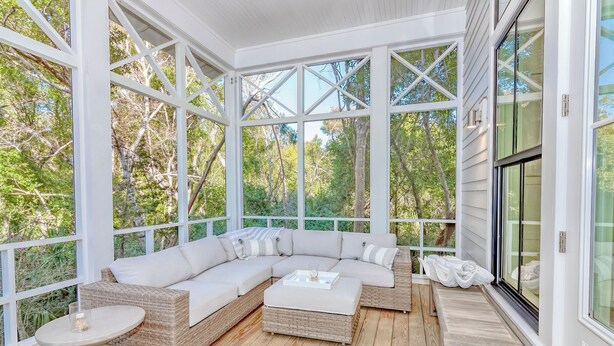 A covered porch with a sectional sofa, a round table, and a bench. - Your dream vacation retreat is nestled in the Maritime Forest (Bald Head Island)