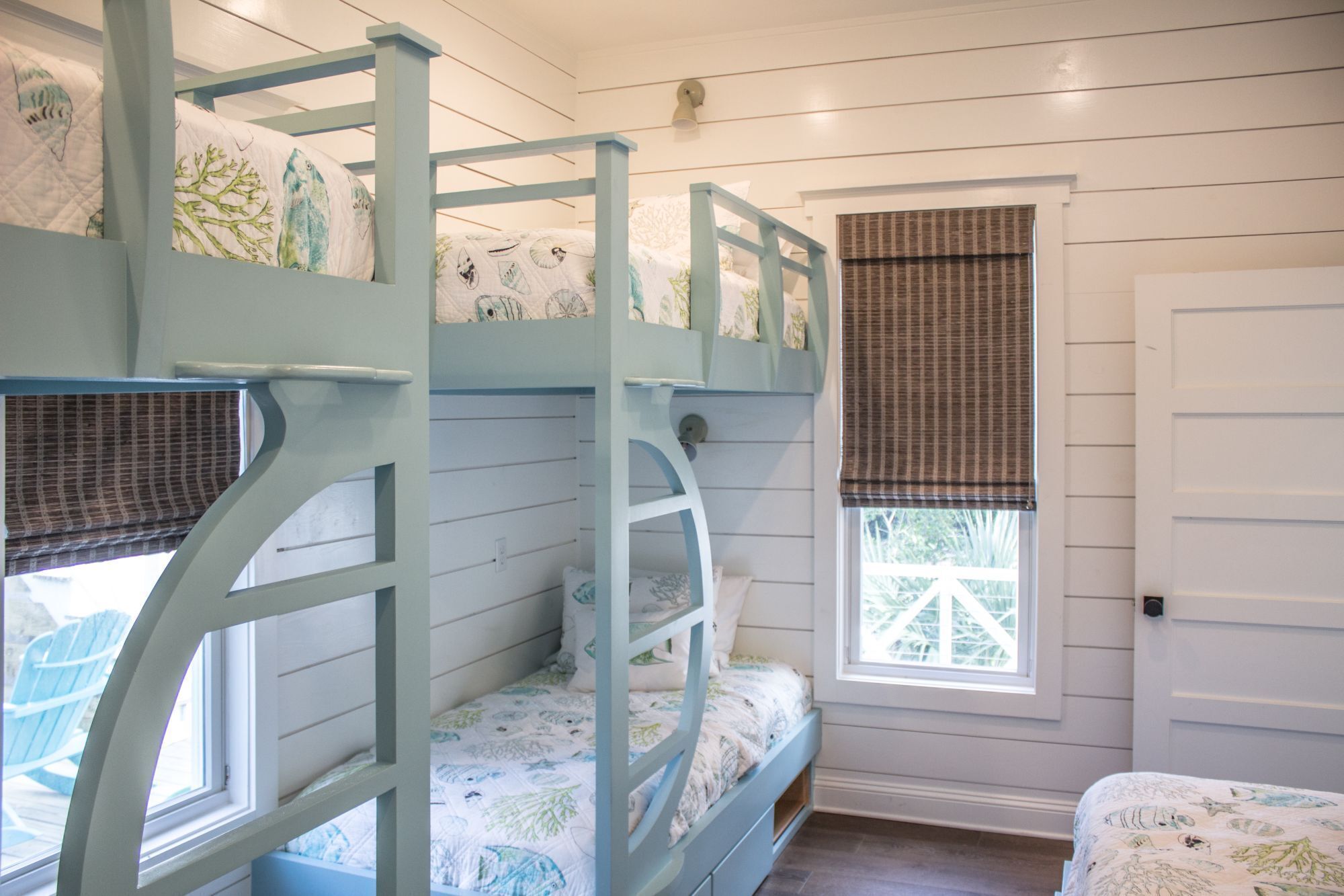 A bunk bed room with a window and a door.