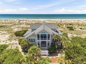 A beachfront house with a large balcony, a covered porch, and a view of the ocean. - Sandbagger is an unforgettable luxury beach retreat with hypnotic views. (Bald Head Island)