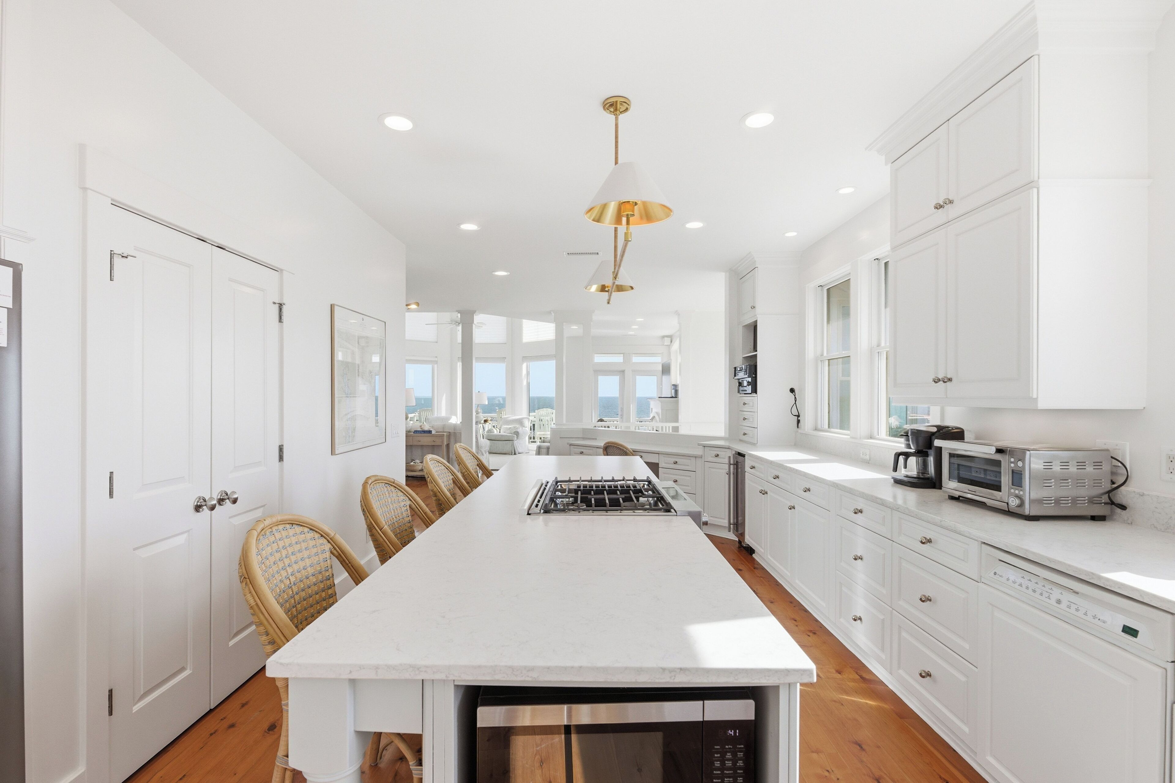 A modern kitchen with white cabinetry, a central island, and a view to the outside.
