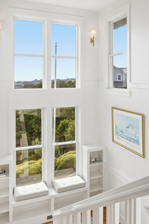 A multi-level interior with white walls, large windows, and a framed picture on the wall. - Executive Retreat HAS IT ALL-privacy, beach proximity (Bald Head Island)