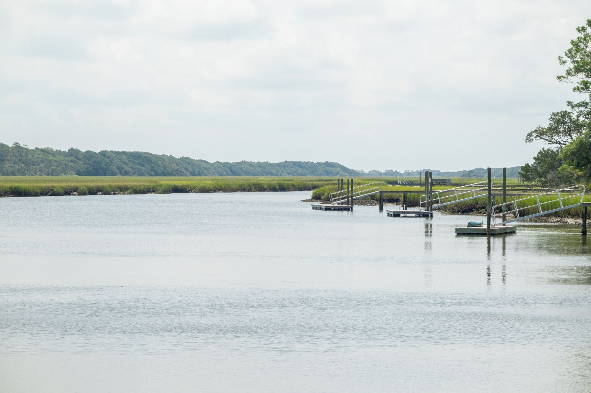 A calm lake with a dock and a bridge.
