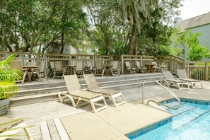 A poolside area with lounge chairs, a wooden deck, and a pool.