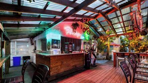 Un espace bar avec un comptoir en bois, des tabourets de bar et un panneau néon.