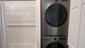 A compact, modern laundry room with two stacked washing machines and a single bathtub. - Spacious home w/dual entrance for added privacy. Near HMT system, dining & shops (Logan)