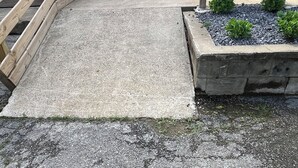 A concrete pathway leading to a wooden structure with a seating area and a planter with green plants. - Spacious home w/dual entrance for added privacy. Near HMT system, dining & shops (Logan)